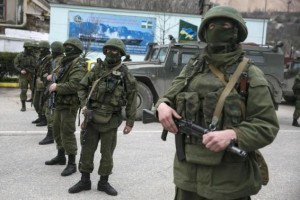 Armed servicemen stand near Russian army vehicles outside a Ukrainian border guard post in the Crimean town of Balaclava